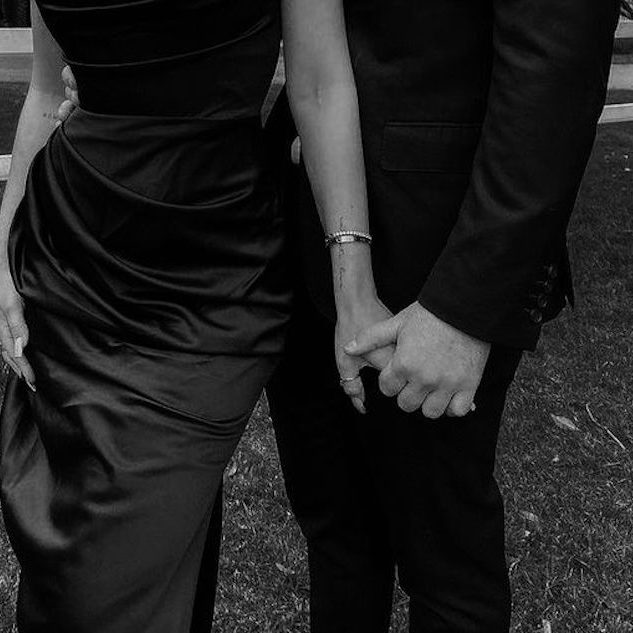 Erotisches Paar stehen nebeneinander und halten sich an den Händen, elegant gekleidet.