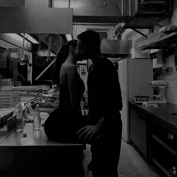 Ein Paar küsst sich in einer dunklen Restaurantküche.