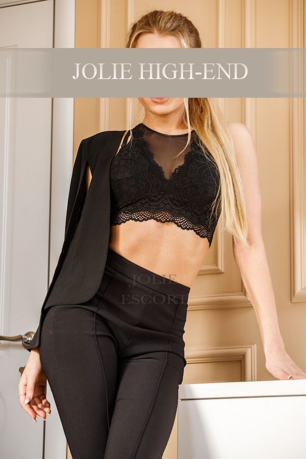 Dünner, blonder Nikki in eleganter schwarzer Kleidung mit transparentem Oberteil.