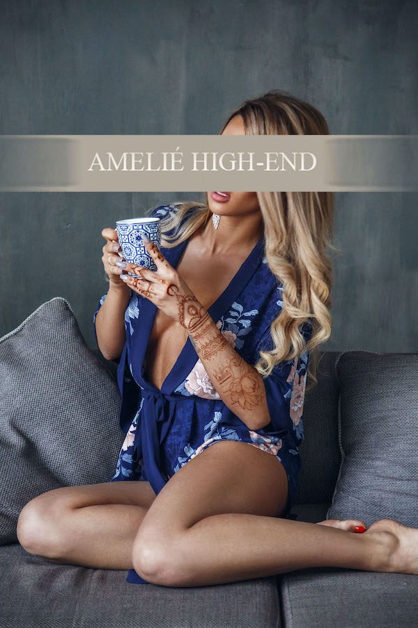 Eine vip escort in einem kimonoähnlichen Kleid, die eine Tasse hält und lächelt.