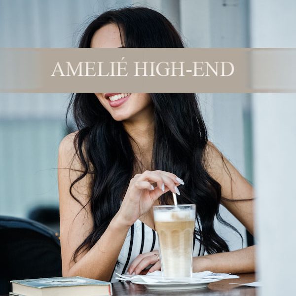 Escort Model Anita in schwarzem BH und Slip, trägt einen Blazer, posiert vor hellem Hintergrund.