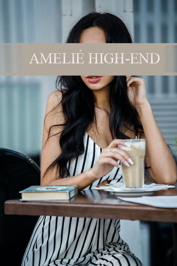 Frau mit langen, dunklen Haaren trinkt Kaffee an einem Tisch, Bücher liegen daneben.