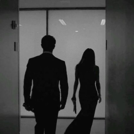 Silhouetten von zwei Personen in eleganter Kleidung, die einen Raum betreten.