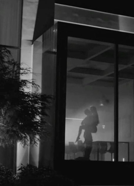 Silhouette einer Person, die im Schatten eines Fensters steht, mit einem sanften Lichtschein.